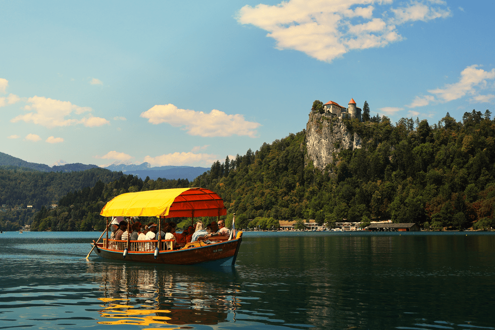 A traditional pletna boat crossing Lake Bled toward the cliffside castle