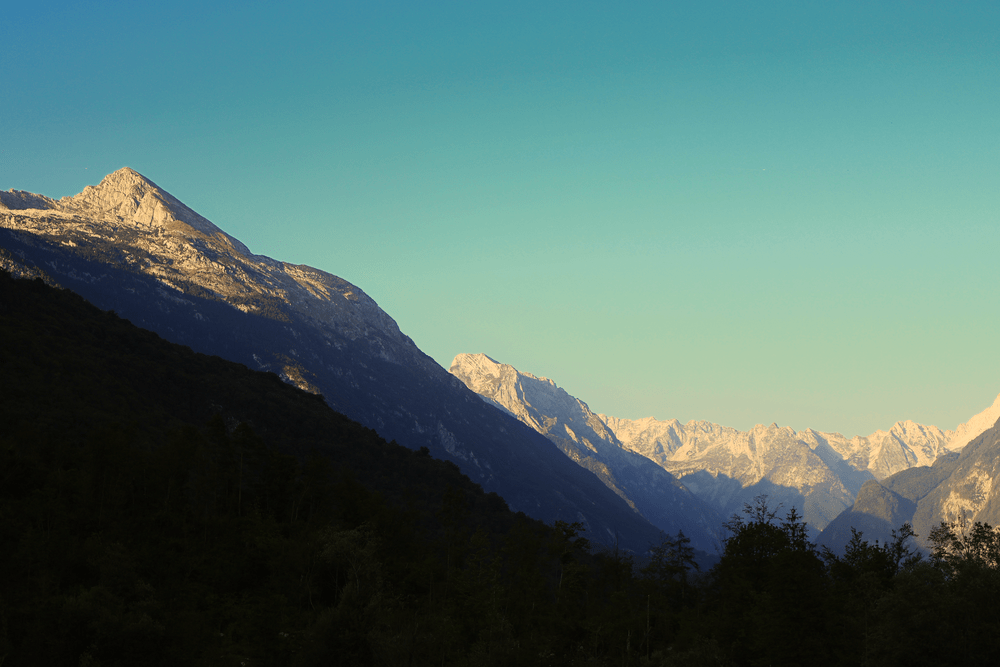 Silhouetted mountain peaks at sunset along Vršič Pass